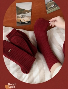 Macro detail of dark red ribbed knit wool crew socks with warm vertical texture