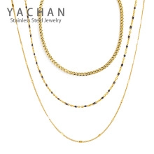 Close-up of triple-layered golden stainless steel necklace with round bead accents