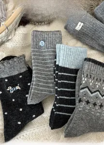 Macro shot of assorted grey wool blend mid-calf socks with embroidery on white fleece