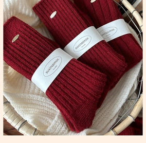 Three pairs of warm red wool socks with ribbed texture and elegant gold metal logo brand