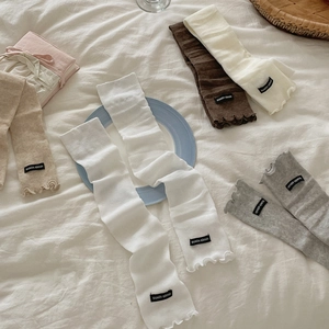 Vertical ribbed knit leg warmers with ruffle trim in minimalist neutral pastel colors