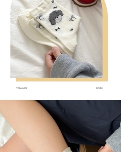Detail of white cotton socks featuring cute grey dog embroidery and bow accents