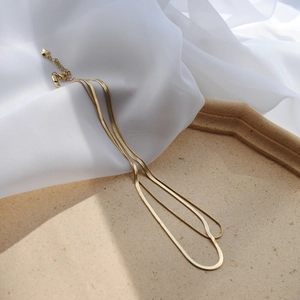 Detail of a double-layered gold snake chain necklace with a heart pendant extension