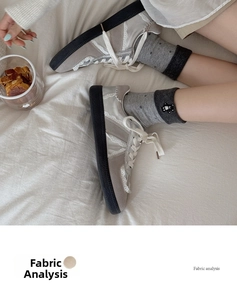 Λεπτομέρεια από γκρι σουέτ sneakers με λευκή δαντέλα και γκρι πουά κάλτσες