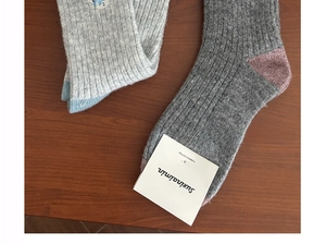 Detail of thick winter wool socks with ribbed texture and snowman embroidery on wood