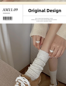 Detail von cremefarbenen Rippstrick-Socken kombiniert mit braunen Slippern für Zuhause