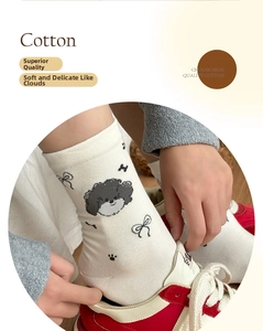 Detail of cream cotton crew socks featuring cute black puppy prints and bow patterns