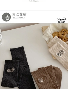 Nahaufnahme von Baumwollsocken mit Hundestickerei, Rippstruktur und Deko-Keksen