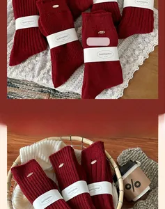 Detail of burgundy wool socks with ribbed texture and gold metal tag in a cozy winter setting