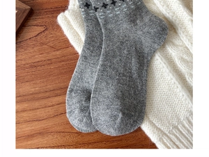 Close-up of gray wool knit socks with black cross detail on a cozy winter background