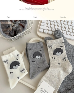 Detailed knit texture of puppy pattern socks in white, grey and oatmeal colors