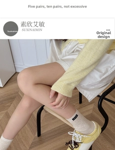 Detail of beige ribbed crew socks with brand woven label on model in cozy interior