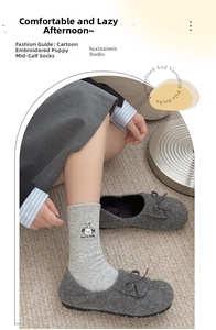 Detail of light gray crew socks with cute cartoon dog embroidery and soft marled texture