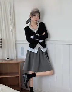 Close-up of women's preppy set with black knit vest, striped shirt and pleated skirt