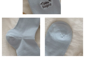 Detail view of light blue knitted cotton socks with dark brown Bebe Bonjour embroidery