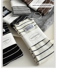 Detail of striped socks with ruffle edges and fabric labels in neutral tones