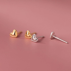 Macro detail of S925 sterling silver heart studs in gold and silver relief finish