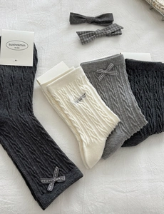 Detailed knit texture of girls cable knit socks with cute bow and flower embroidery