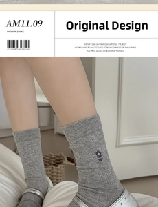 Detail of gray mid-calf socks with floral embroidery and comfortable ribbed cuffs