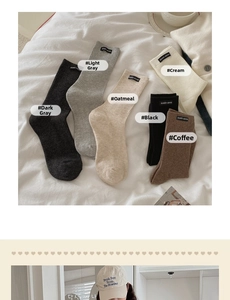 Detail of ribbed knit crew socks in earth tones with brand logo labels on bed linen