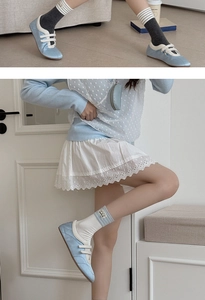 Detail of light blue Mary Jane shoes with triple straps and striped crew socks