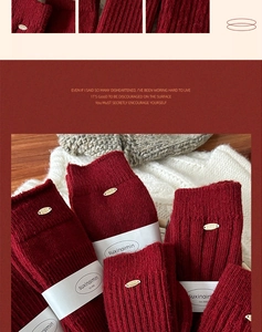 Close-up of ribbed knit wool socks in deep red with elegant golden brand tag detail