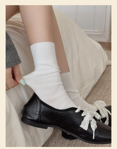 Detail of white ribbed crew socks being stretched to show high elasticity and soft texture