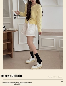 Detail of a chic cream knit cardigan with wavy edges and stylish black mid-calf socks