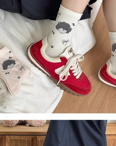 Close-up of white mid-calf socks with cute black puppy pattern and red retro sneakers