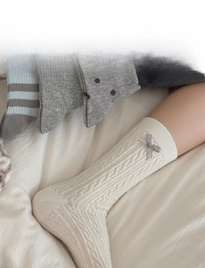 Detail of cream cable knit mid-calf sock with a grey bow and soft textured pattern