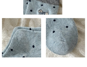 Close-up of light blue wool sock with navy dots and embroidery on knit texture