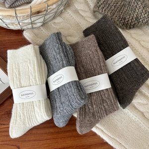 Thick wool twist knit socks in four earth tones presented on a cozy winter blanket
