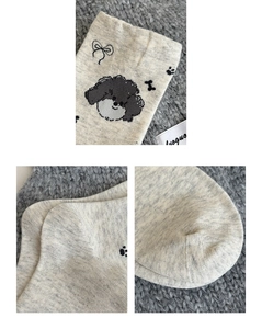 Detailed macro view of gray knitted socks featuring cartoon puppy and bone embroidery motifs