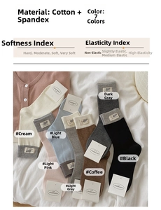 Detail of seven colored cotton crew socks with MOUSE woven labels on white linen