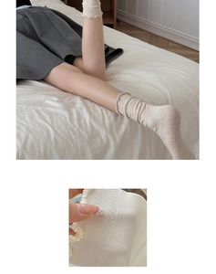 Close-up of beige cotton socks featuring ruffled lettuce edges and ribbed knit texture