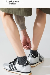 Detail of grey knitted crew socks worn with silver retro sneakers and olive cargo shorts
