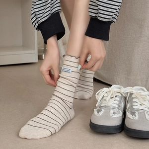 Japanese style beige mid-calf socks with thin brown stripes and a minimalist fabric label