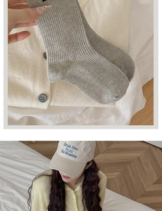 Detail of grey ribbed cotton socks paired with a cream cardigan and embroidered baseball cap