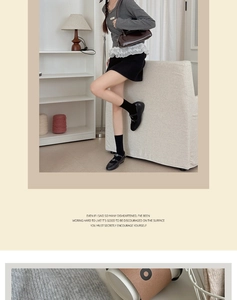 Detail of grey knitted sweater with metal chain and black socks with leather shoes