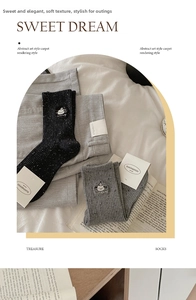 Detail of speckled knit crew socks with cute cartoon puppy embroidery and baby text