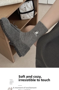 Detailed view of grey crew socks with cute cartoon puppy embroidery and soft flecked yarn