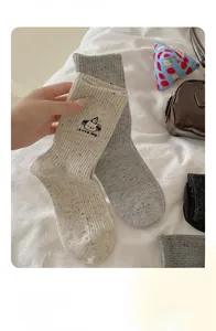 Detail of knitted cotton socks with cute dog embroidery and subtle speckled texture