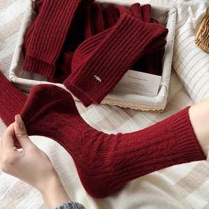 Deep red warm wool mid-tube socks with vertical ribbed knit texture in a rustic basket