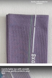Detail of purple compression socks featuring striped patterns and knitted DXS lettering