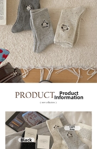 Detailed embroidery of a cartoon dog on soft speckled knit mid-calf casual socks