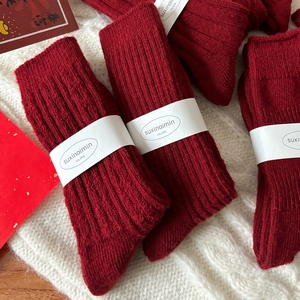 Festive red wool crew socks with ribbed texture and decorative holiday packaging