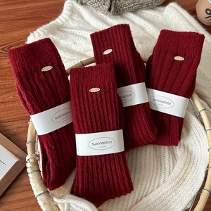 Winter wine red wool socks with vertical stripes and gold button in a cozy basket