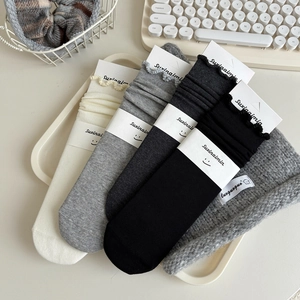 Four pairs of ribbed cotton ruffle socks in white, grey and black on a tray