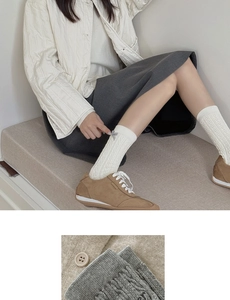 Detail of white cotton cable knit crew socks with a delicate side bow and wood button