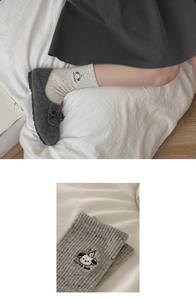 Detailed close-up of grey knit socks with cute dog embroidery and cute dog text